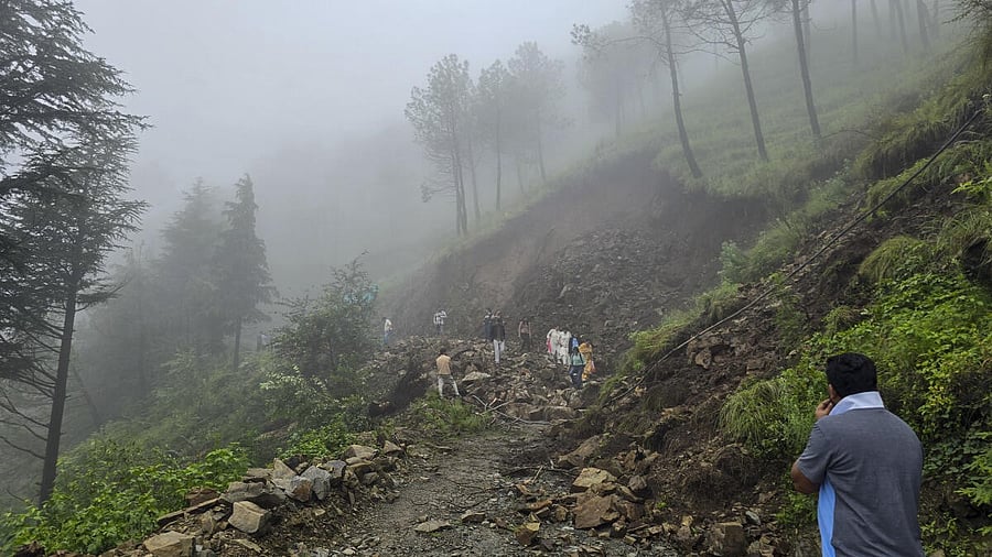 <div class="paragraphs"><p>People make their way through the debris after a road got blocked due to a landslide following heavy rainfall, in Shimla.</p></div>