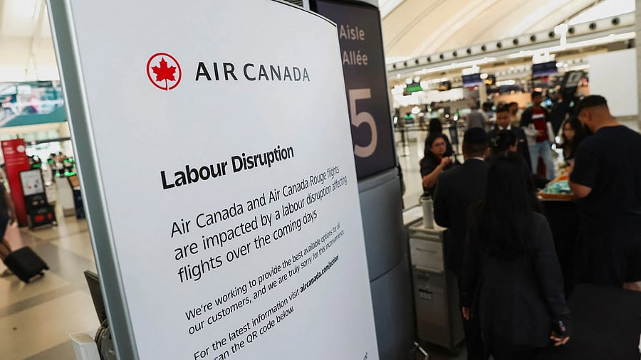 <div class="paragraphs"><p>Air Canada workers assist a passenger at a kiosk while handling flight disruptions, ahead of a potential strike by the airline’s flight attendants, at Toronto Pearson International Airport in Mississauga, Ontario</p></div>