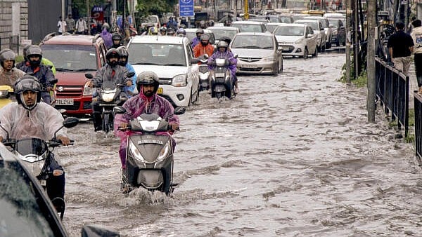 <div class="paragraphs"><p>Commuters move through a waterlogged road after heavy rainfall.</p></div>