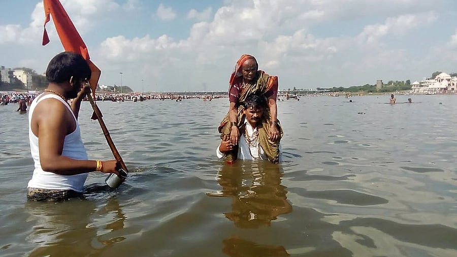 Sadashiv Bane carries his 102-year-old mother Satyavva on his shoulders for a bath in River Chandrabhaga at Pandharpur.