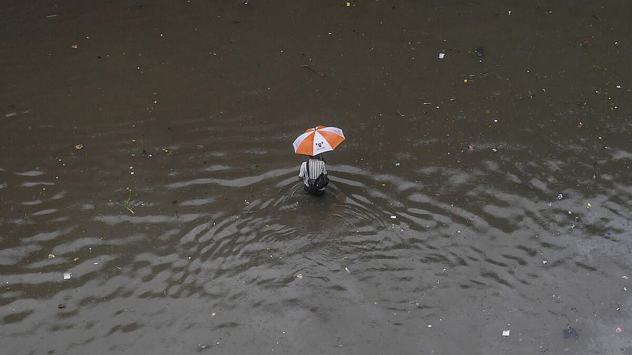 <div class="paragraphs"><p>A commuter makes his way through a waterlogged road amid rainfall, in Mumbai, Tuesday, Aug. 19, 2025.</p></div>