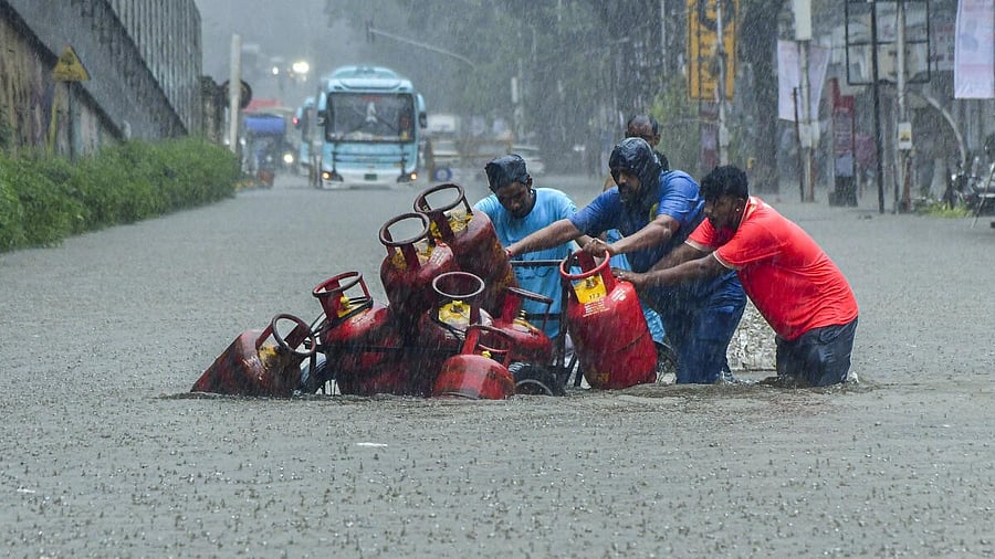 <div class="paragraphs"><p>People move a cart with domestic gas cylinders through a waterlogged road following rainfall</p></div>
