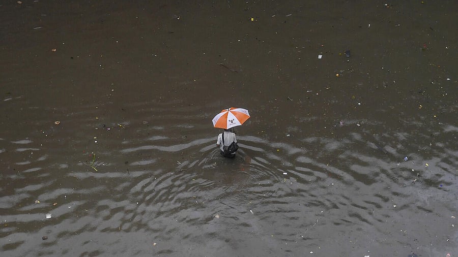 <div class="paragraphs"><p>A commuter makes his way through a waterlogged road amid rainfall, in Mumbai.</p></div>