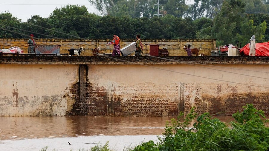<div class="paragraphs"><p>A family with their belongings takes refuge over a roof of their house near Chenab River, following the monsoon rains and rising water level in Wazirabad</p><p></p></div>