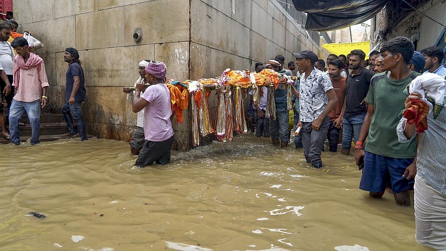 <div class="paragraphs"><p>People carrying mortal remains of a relative wade through the flooded Manikarnika Ghat area as the swollen Ganga river inundates nearby areas during the monsoon season, in Varanasi, Uttar Pradesh.&nbsp;</p></div>