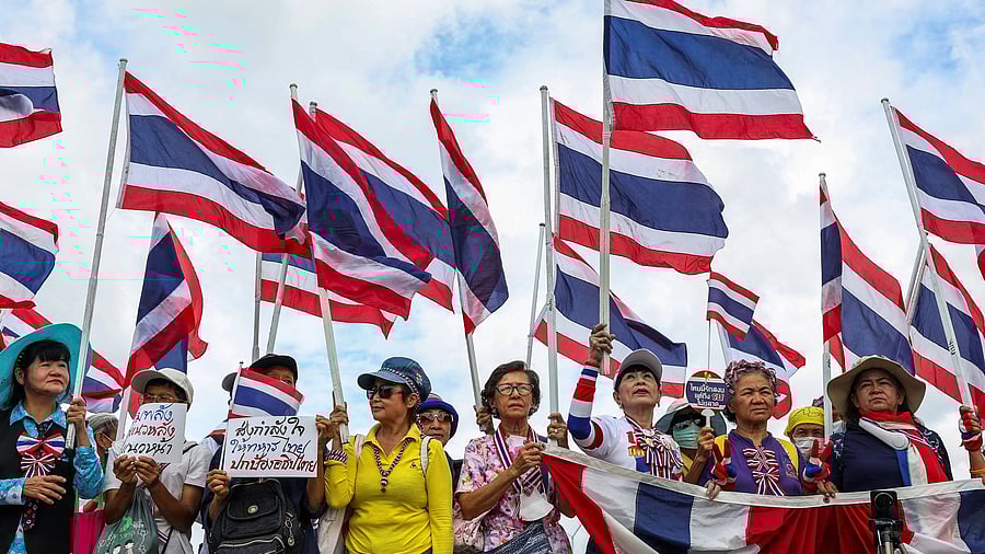 <div class="paragraphs"><p>Members of a royalist group hold Thai national flags and signs.</p></div>