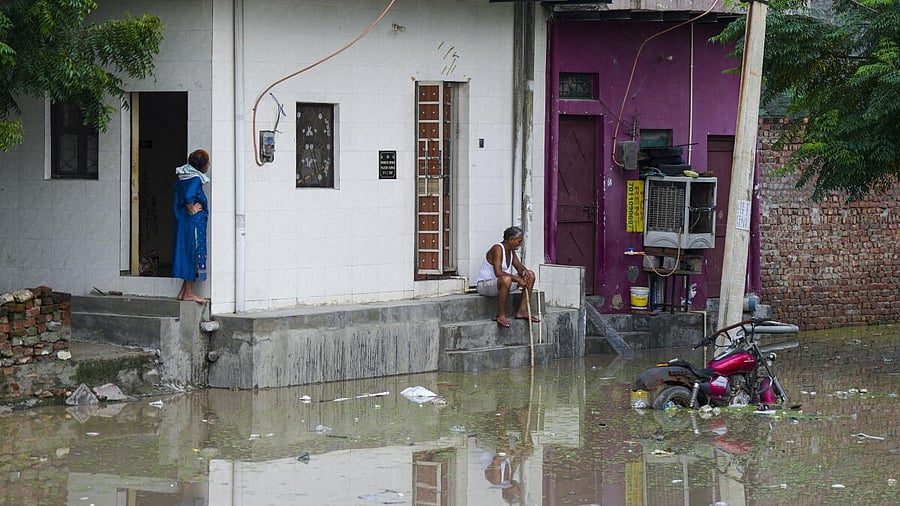 <div class="paragraphs"><p>People sit outside their houses amid a flooded area  in New Delhi. Image for representational purposes.&nbsp;</p></div>