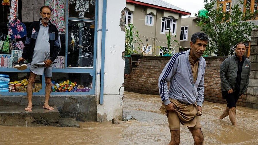 <div class="paragraphs"><p>People wading through a flooded road following heavy rains in the Tailbal area on the outskirts of Srinagar on Wednesday. <br></p></div>