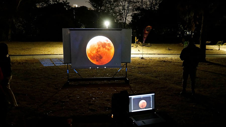 <div class="paragraphs"><p>People watch on a video beam screen a full moon during a "Blood Moon" total lunar eclipse.</p></div>