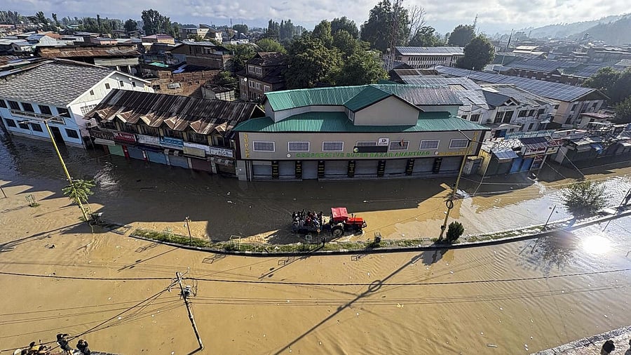 <div class="paragraphs"><p>People wade through a flooded area on a tractor, in Anantnag.</p></div>