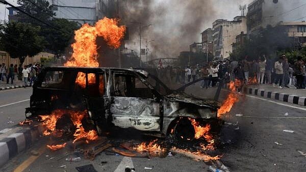 <div class="paragraphs"><p>People stand near a vehicle torched by the demonstrators during a protest against corruption and the government’s decision to block several social media platforms, in Kathmandu, Nepal.</p></div>