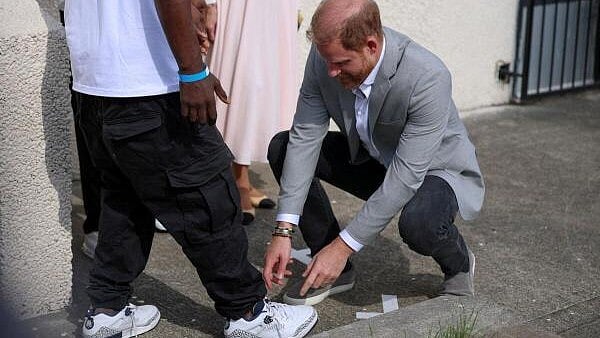 <div class="paragraphs"><p>Britain's Prince Harry checks a shoe of Trevor Rose, head of the Community Recording Studio (CRS), a grassroots institution providing opportunities for young people, during a visit to CRS, in Nottingham, Britain.</p></div>