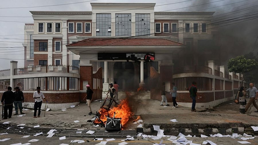 <div class="paragraphs"><p>Demonstrators walk past burning furnitures outside a government building vandalized during a protest in Nepal. </p></div>