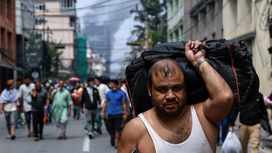 <div class="paragraphs"><p>Smoke rises in the distance as a prisoner carrying his belongings walks back to Dilli Bazaar jail, after escaping and being sent back by the Nepalese army following anti-corruption protest in Kathmandu, Nepal.</p></div>
