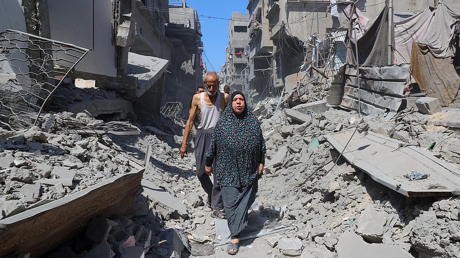 <div class="paragraphs"><p>Palestinians walk amid rubble, after an Israeli strike hit an evacuated residential building at Shati (Beach) refugee camp, amid the Israeli military offensive, in Gaza City.</p></div>