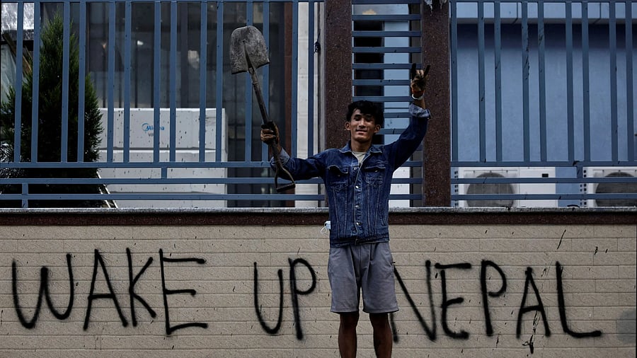 <div class="paragraphs"><p>Sabin Tamang, 20, who works in a restaurant and participated in a Gen-Z protest, holds up a shovel while posing for a photograph next to graffiti as he takes part in a cleaning campaign following Monday's deadly anti-corruption protests in Kathmandu.</p></div>