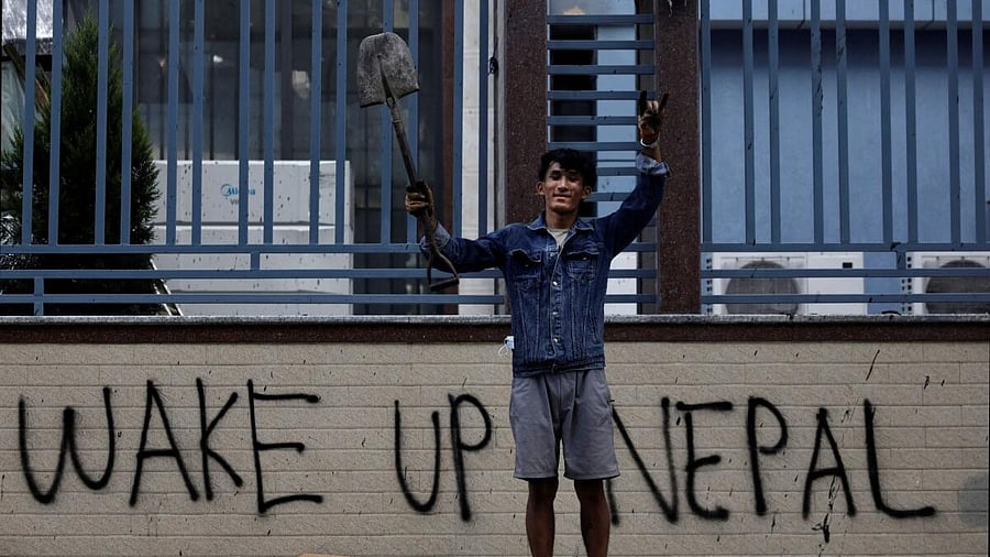 <div class="paragraphs"><p>Sabin Tamang, 20, who works in a restaurant and participated in a Gen-Z protest, holds up a shovel while posing for a photograph next to a graffiti as he takes part in a cleaning campaign following Monday's deadly anti-corruption protests in Kathmandu, Nepal, September 10, 2025.</p></div>
