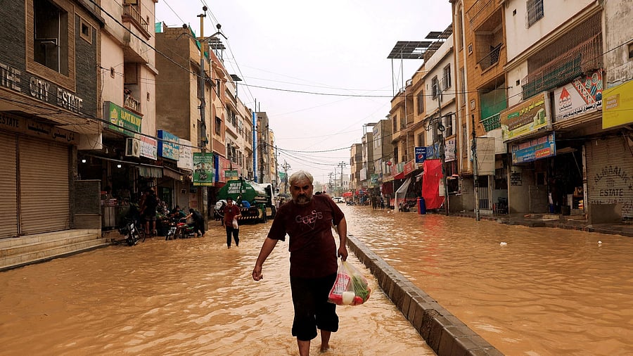 <div class="paragraphs"><p>A resident carries a bag of groceries as he wades through a flooded street after a rain, following a recent monsoon season, in Karachi, Pakistan </p></div>