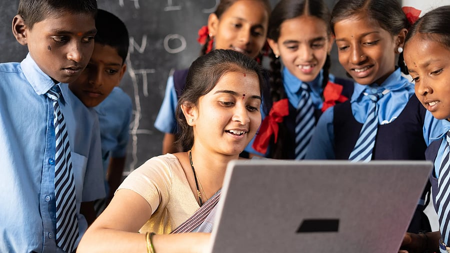 <div class="paragraphs"><p>Young Indian teacher teaching on laptop with school uniform students at classroom - concept of development, technology and digital education</p></div>