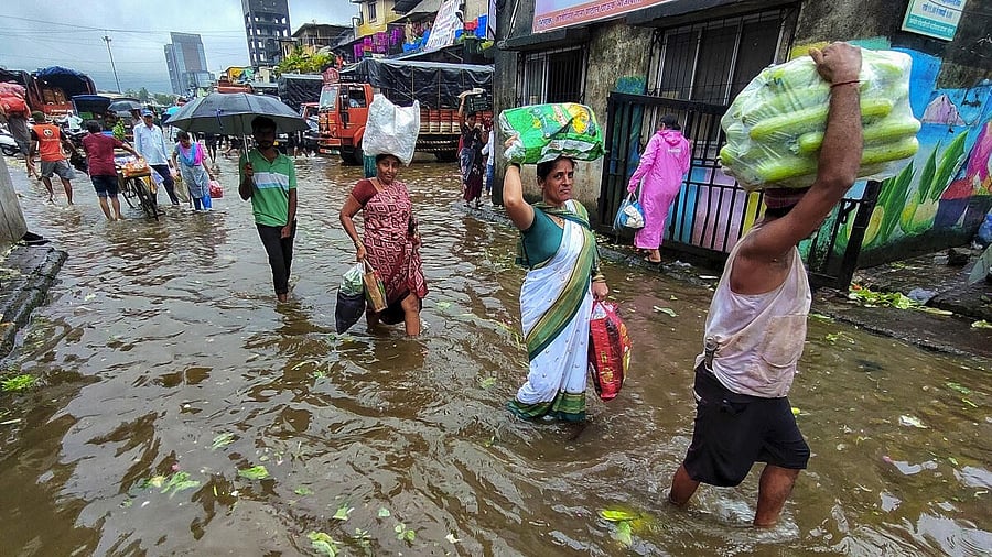 <div class="paragraphs"><p>People carrying their belongings wade through waterlogged road amid rainfall, in Navi Mumbai, Monday, Sept. 15, 2025.</p></div>