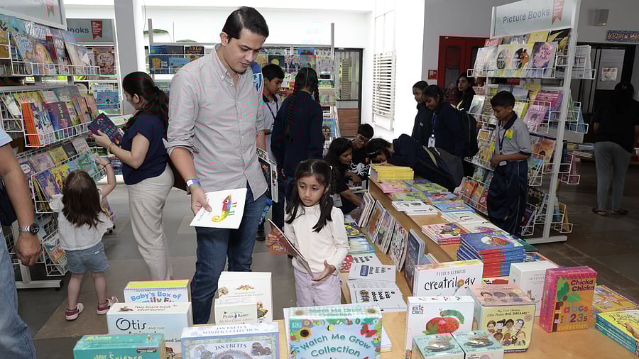 A man and his daughter are busy browsing through children's books at Neev Literature Festival in Bengaluru on Saturday. 