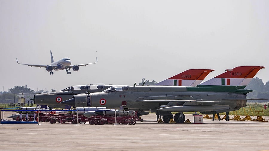 <div class="paragraphs"><p>A passenger plane passes by as Indian Air Force MiG-21 aircraft are parked during rehearsals, ahead of the ‘MiG-21 Operational Flying Culmination Ceremony’ at Chandigarh Air Force Station (AFS), in Chandigarh, Wednesday, Sept. 24, 2025.</p></div>