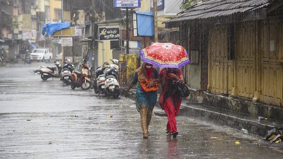 <div class="paragraphs"><p>Commuters walk down a street amid rain, in Navi Mumbai.</p></div>