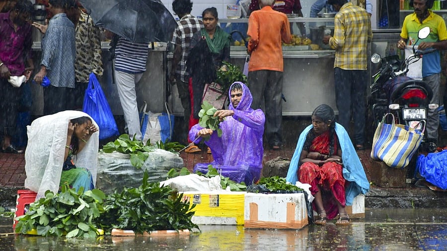 <div class="paragraphs"><p>Street vendors protect themselves with plastic sheets amid rainfall, in Mumbai.</p></div>
