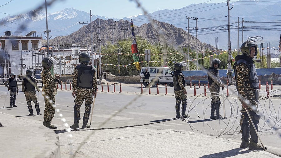 <div class="paragraphs"><p>Security personnel stand guard on a road amid curfew.</p></div>