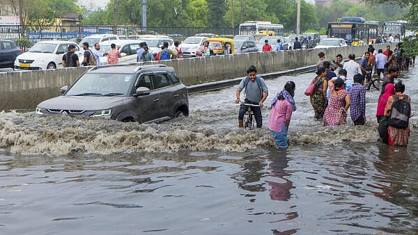 <div class="paragraphs"><p>Commuters move on a waterlogged service road in Delhi.</p></div>