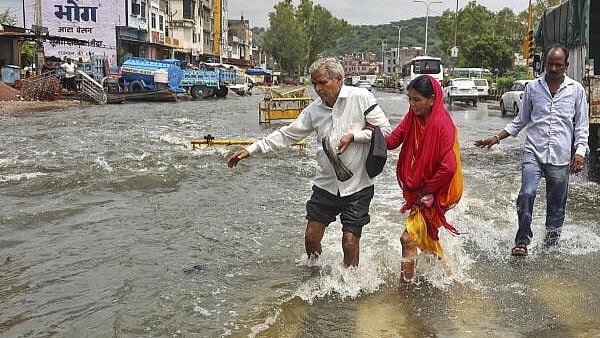 <div class="paragraphs"><p>Pedestrians cross a waterlogged road after heavy overnight rainfall.</p></div>