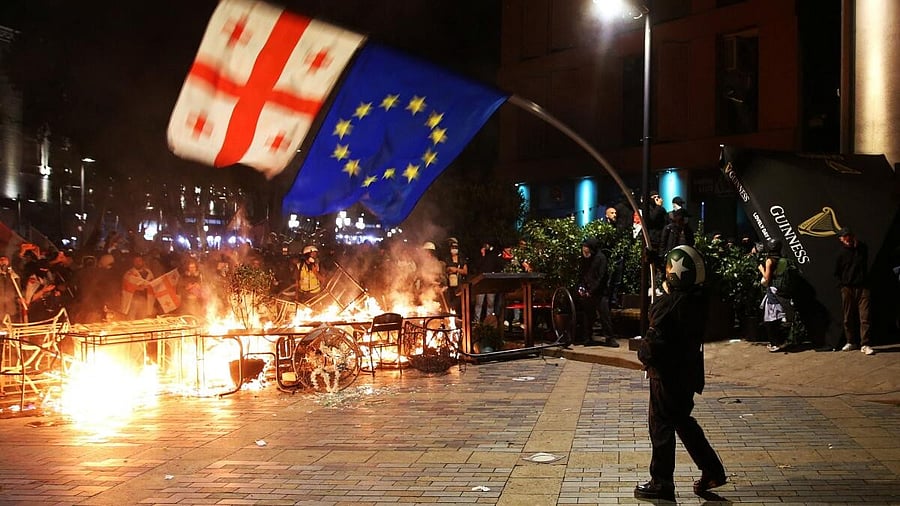 <div class="paragraphs"><p>A protester waves Georgian and EU flags in front of a burning barricade during an opposition rally on the day of local elections in Tbilisi, Georgia October 4, 2025.</p></div>