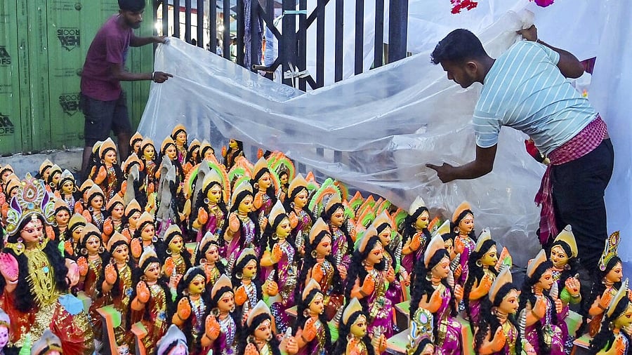 <div class="paragraphs"><p>Workers cover the idols of Goddess Lakshmi with a plastic sheet on the eve of the 'Lakshmi Puja', in Agartala</p></div>