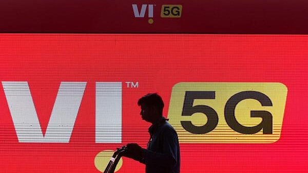 <div class="paragraphs"><p>A man walks across the LED display board showing the logo of Vodafone Idea.</p></div>
