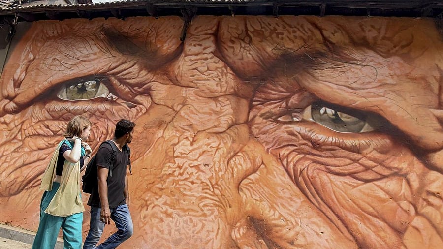 <div class="paragraphs"><p>A couple walks past a painting on a wall which will be part of the 4th edition of 'Kochi Muziris Biennale', an international exhibition of contemporary art held in 2018, in Kochi.</p></div>