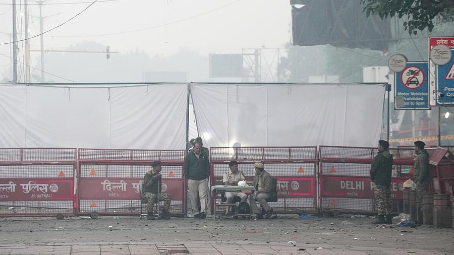 <div class="paragraphs"><p>Police personnel stand guard near an area covered with white cloth in view of the blast that occurred near Red Fort Metro Station on Monday, killing at least nine people and gutting several vehicles, in New Delhi</p></div>