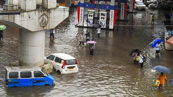 <div class="paragraphs"><p>Commuters wade through a waterlogged road amid rainfall in Mumbai.</p></div>