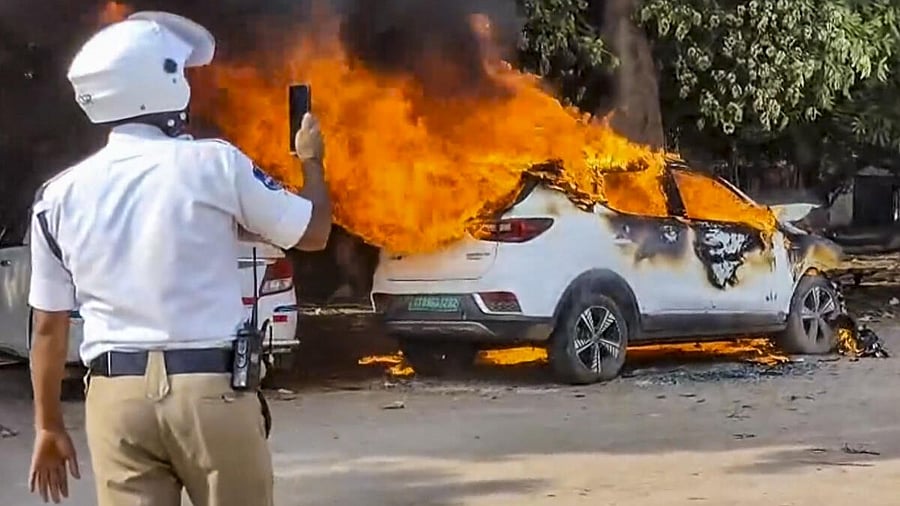 <div class="paragraphs"><p>A police official captures footage as fire engulfs an electric car, in Hyderabad, Telangana.</p></div>