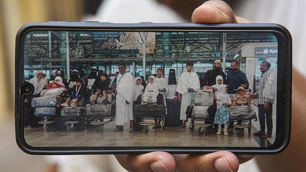 <div class="paragraphs"><p>A man displays a photo of Syed Naseeruddin and his family while departing for Saudi Arabia, during police investigations, in Hyderabad</p></div>