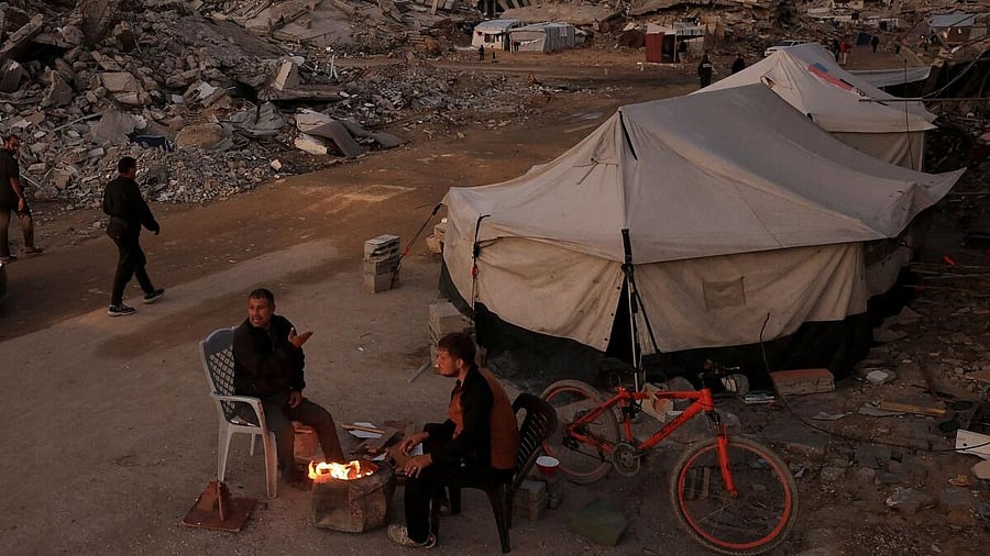 <div class="paragraphs"><p>Palestinians sit next to a fire, amid a ceasefire between Israel and Hamas, in Gaza City.</p></div>