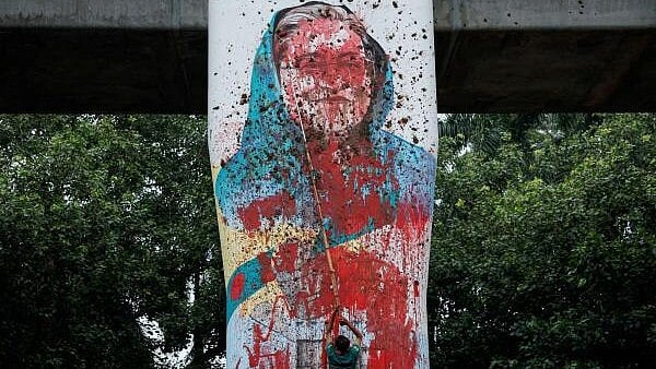 <div class="paragraphs"><p>A protester vandalises a mural of Bangladeshi Prime Minister Sheikh Hasina with paint in Dhaka.</p></div>