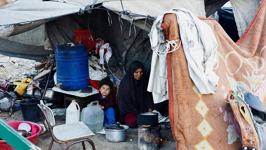 <div class="paragraphs"><p>Palestinian family prepares food over a fire stove in front of their tent in a camp on a rainy day in Nuseirat, central Gaza Strip.</p></div>