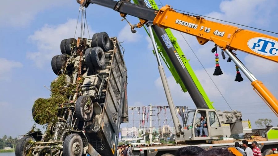 Two cranes pull the submerged 12-wheeler truck out of the lake.