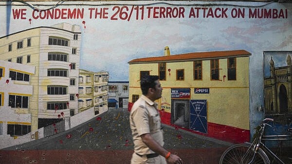 <div class="paragraphs"><p>A police constable walks past a mural depicting Nariman House, one of the sites of the 2008 Mumbai terror attacks, on the eve of the anniversary of the gruesome incident, in Mumbai, Tuesday.</p></div>