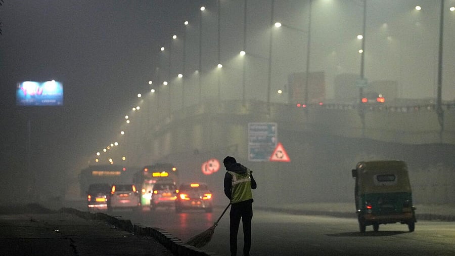 <div class="paragraphs"><p>A sanitation worker cleans a road on a cold and smoggy winter morning in Delhi</p></div>