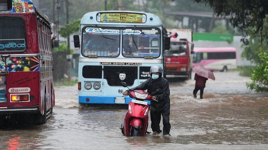 <div class="paragraphs"><p>People and vehicles wade through a waterlogged street following heavy rainfall in Kelaniya</p><p></p></div>