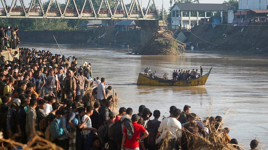 <div class="paragraphs"><p>People ride a wooden boat to cross a river as others wait, at an area hit by deadly flash floods following heavy rains in Bireuen Regency, Aceh, Indonesia.</p></div>