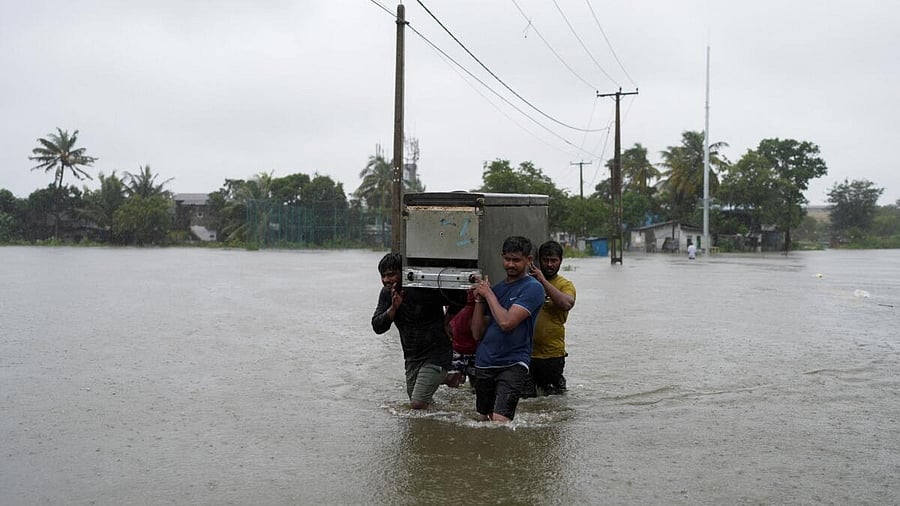 <div class="paragraphs"><p>People carrying a refrigerator wade through the flooded street, following heavy rainfall in Wellampitiya, Sri Lanka, November 28, 2025.</p></div>
