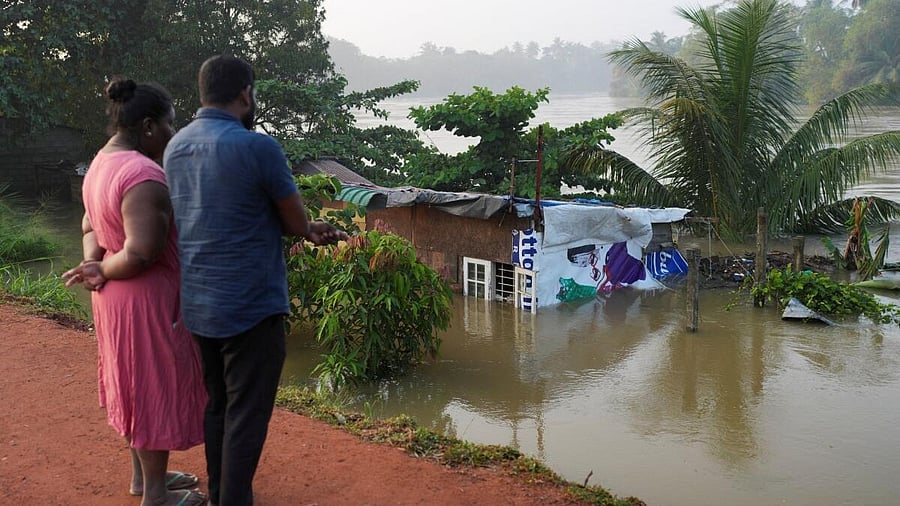<div class="paragraphs"><p>People look towards a house partially submersed by the flood, following Cyclone Ditwah in Peliyagoda, Sri Lanka.</p></div>