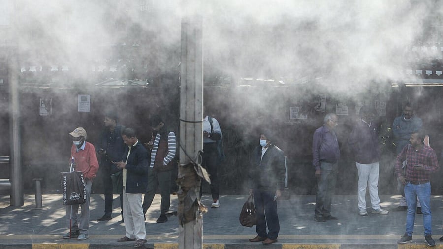 <div class="paragraphs"><p>Commuters stand amidst water being sprayed to curb air pollution, in New Delhi</p></div>